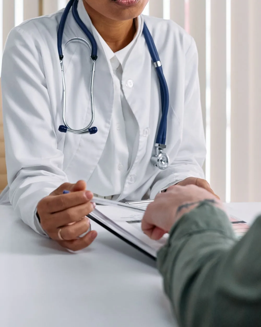 A clinician reviewing notes with a patient across a desk